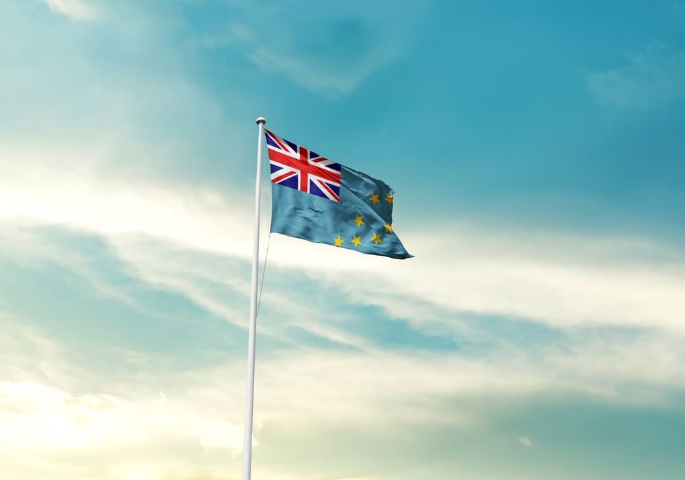 Tuvalu flag is waving on a tall flagpole among the clouds. Tuvalu national flag for independence day.

