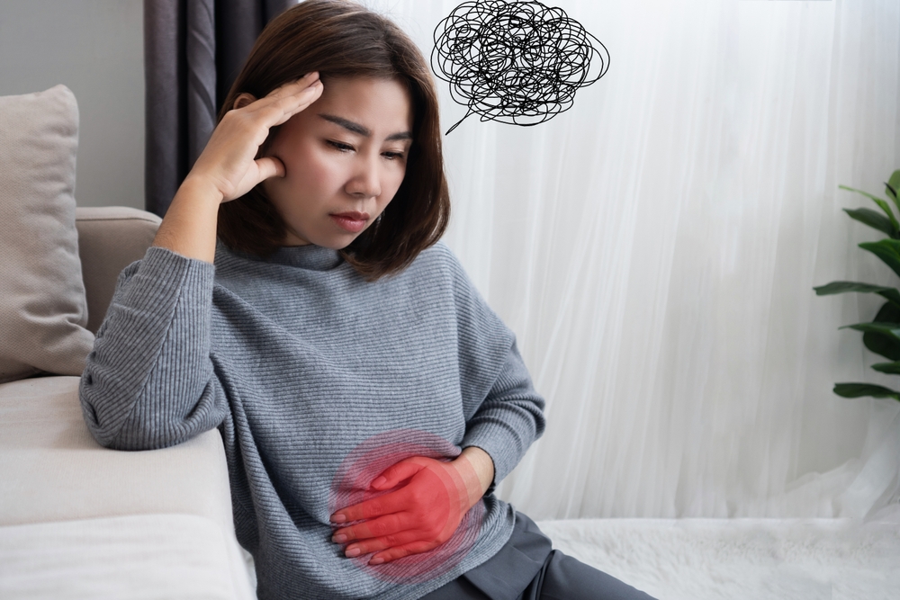 Asian woman suffering from nervous stomach, gut brain axis , feeling discomfort, pain ,connection between stress and digestive discomfort
