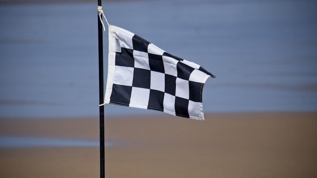 Black and white checkered flag designating surfing area where swimming is prohibited due to risk from fast-moving surfboards.