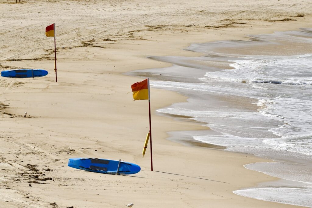 Red and yellow striped flags marking the lifeguard-protected swimming area where rescue personnel and safety equipment are stationed.