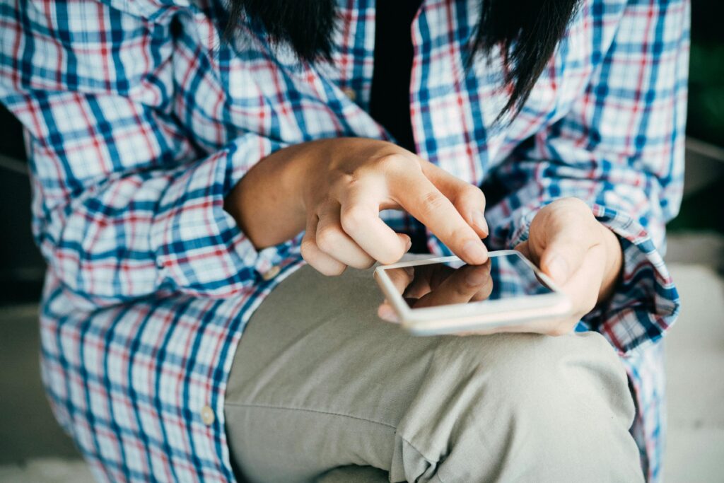 Hands scroll across a smartphone screen, the small gestures reflecting overthinking and cautious communication.