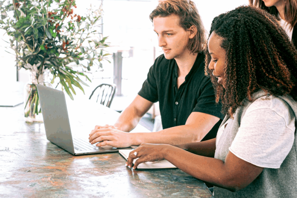Man Working on a Laptop while Woman Takes Notes