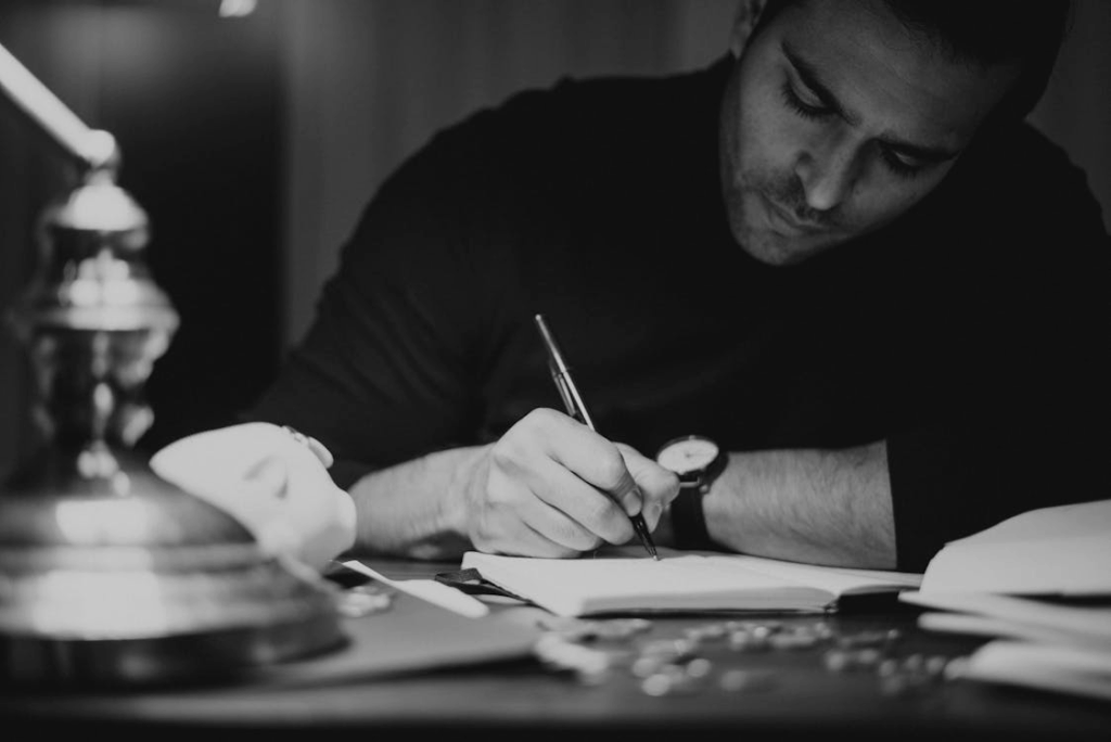 man taking notes in copybook in dark home office