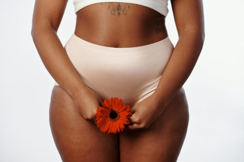 A Woman in White Underwear Holding a Daisy Flower