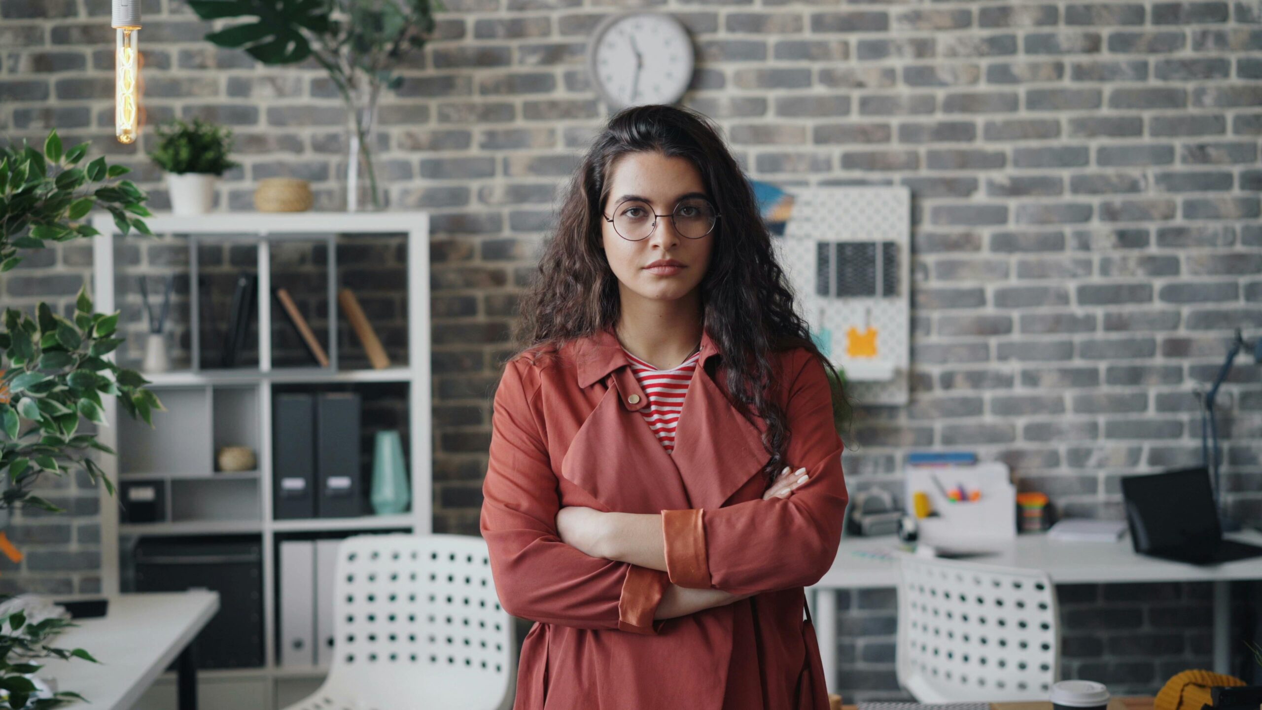 A woman standing in an office with her arms crossed