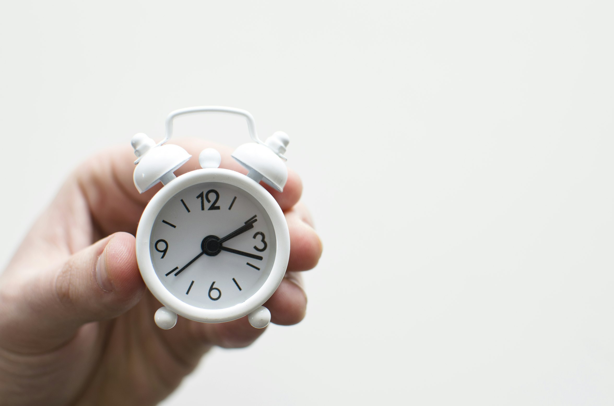 person holding a small white clock