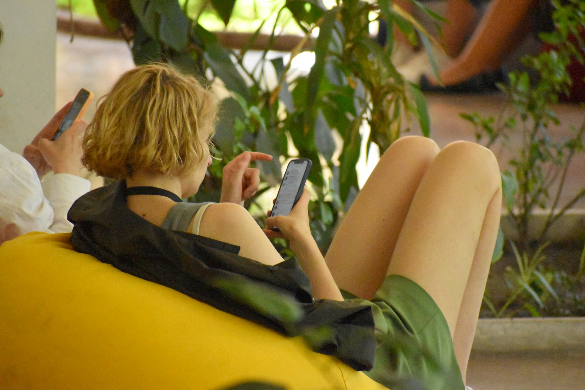 young female with a mobile phone sitting on the bag chair in the conference lounge room.