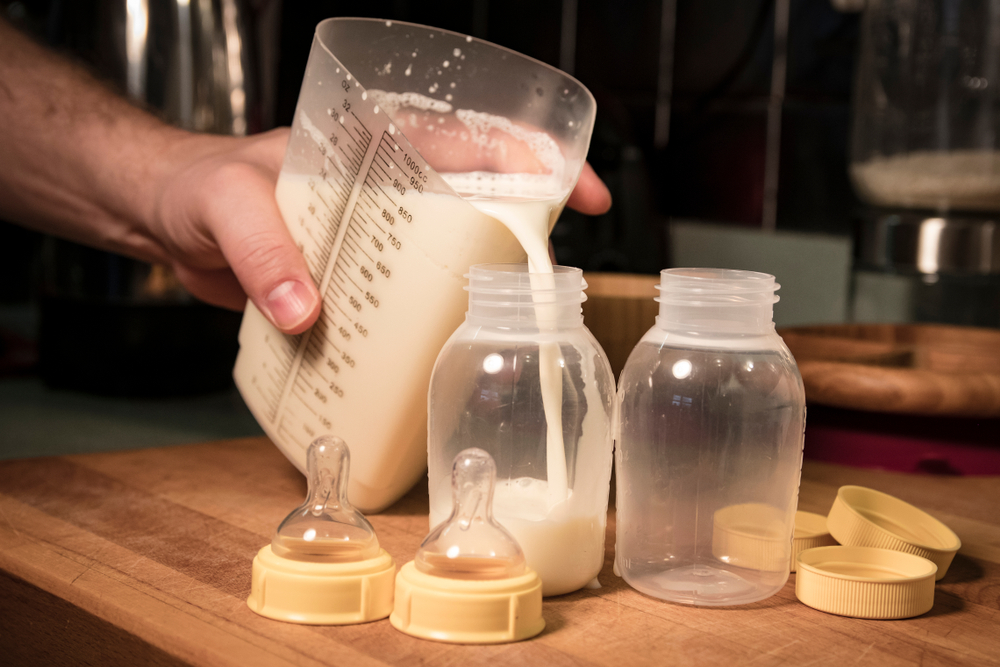 Pouring measured breast milk or formula into baby bottles.