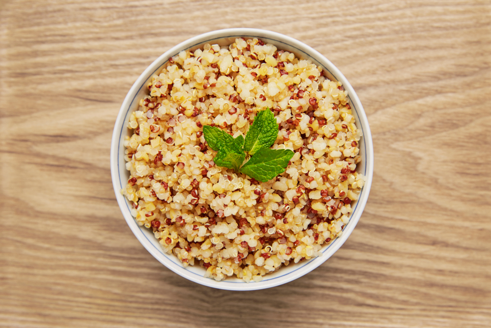 Cooked quinoa bowl on wood background
