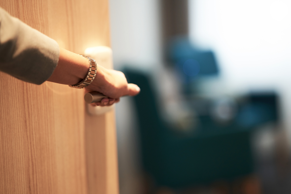 Half-open door of a hotel bedroom with hand