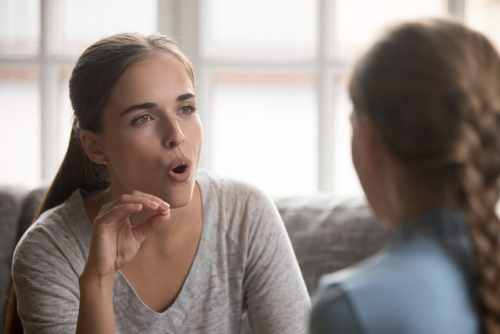 Caring young Caucasian mother study together with small daughter teach kid pronounce voice sounds. Loving mom or teacher speech therapist learn practice pronunciation exercises with little girl child.