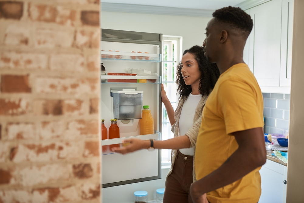 Young multiethnic couple looking for something in their kitchen fridge