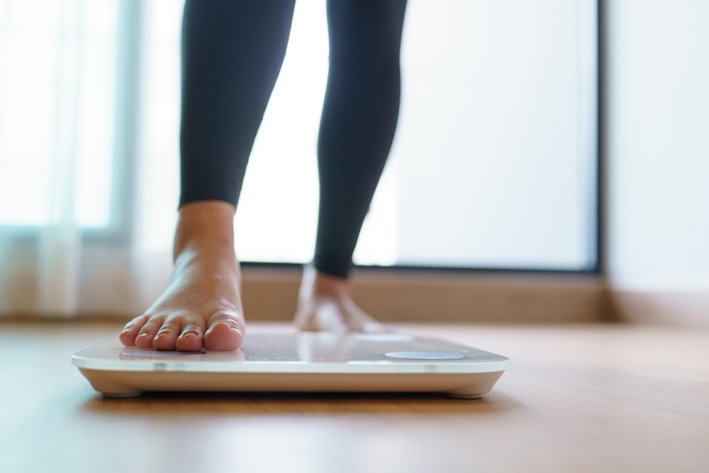 Lose weight. Fat diet and scale feet standing on electronic scales for weight control. Measurement instrument in kilogram for diet