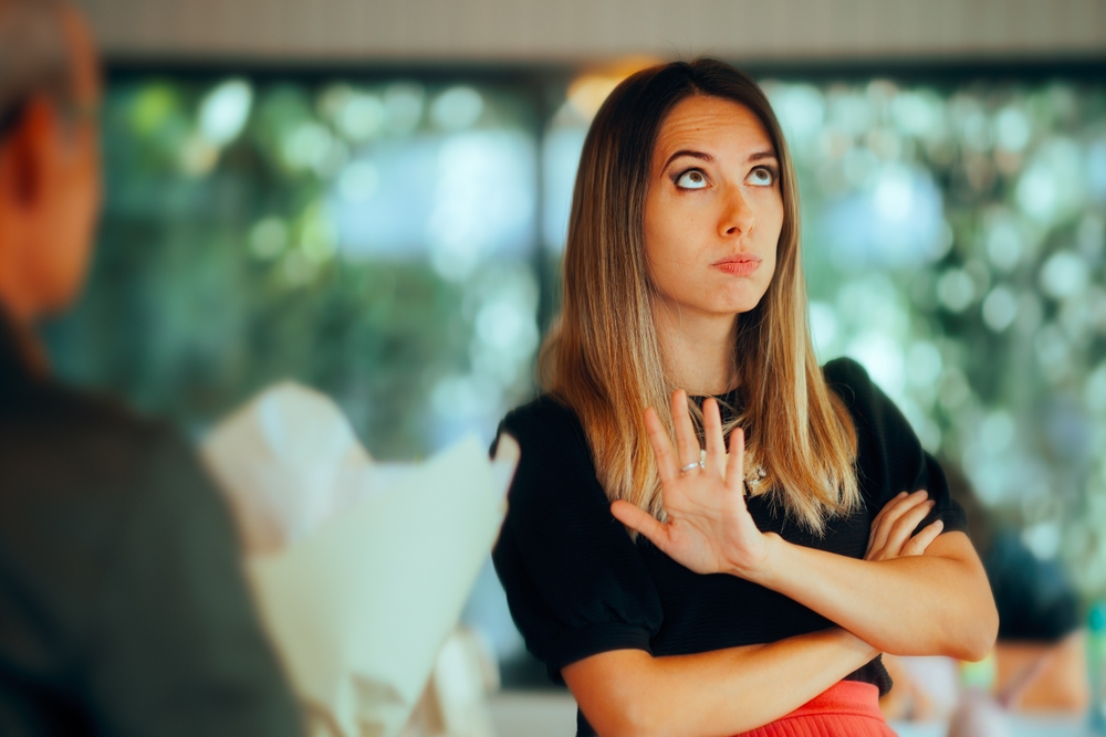 Woman Refusing a Flower Bouquet from an Unwanted Suitor. Upset unforgiving girl not accepting the apology gesture of her admirer
