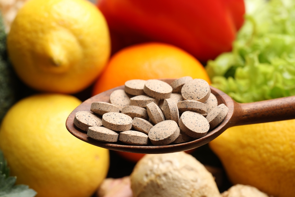 Dietary supplements. Spoon with pills over food products, closeup