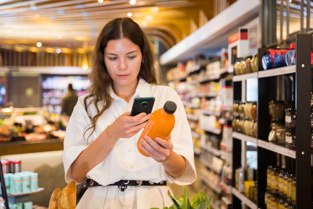 Focused girl chooses carrot juice in the health food department of a supermarket, carefully studying its composition..on the bottle