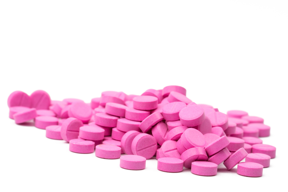 Pile of warfarin pink tablet pills on white background. Warfarin for treatment deep vein thrombosis. Anticoagulant medicine. Pharmacy drug store product. Pharmaceutical industry. Anticoagulation.