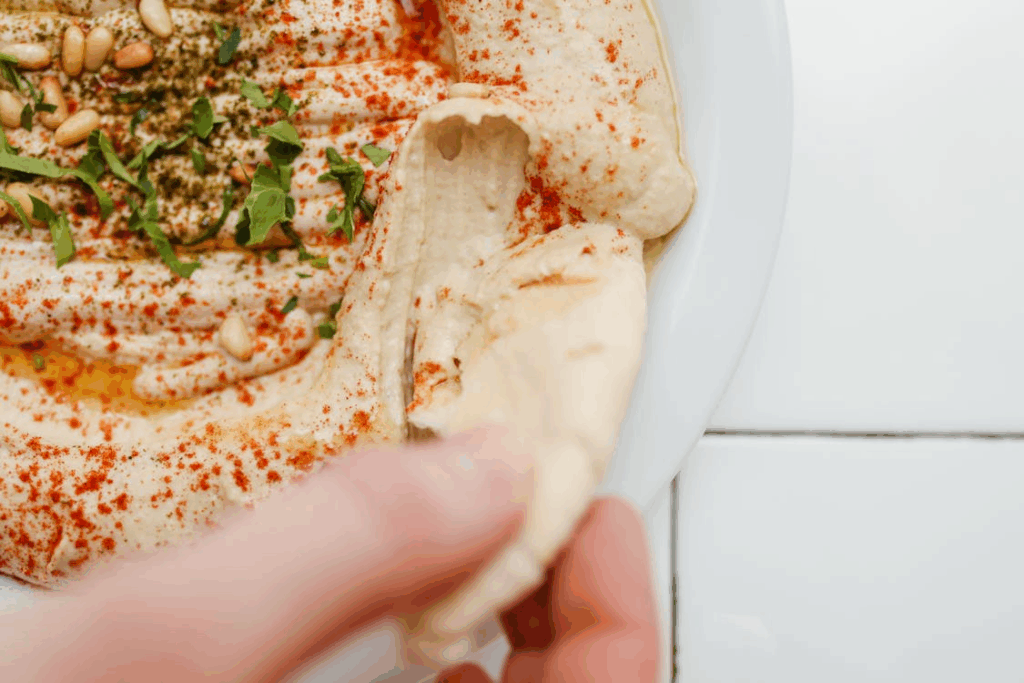 Close-Up Shot of a Person Holding a Humnus Bread