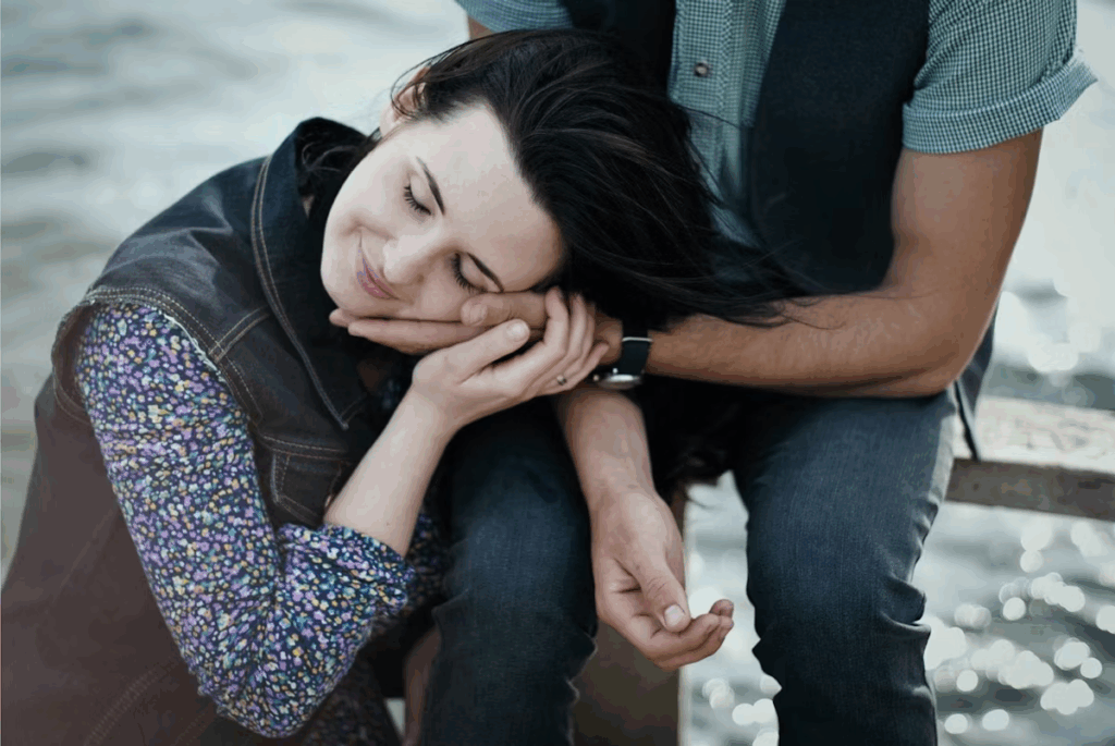 the woman is lying on her husband’s arm. And he carefully supports her head.