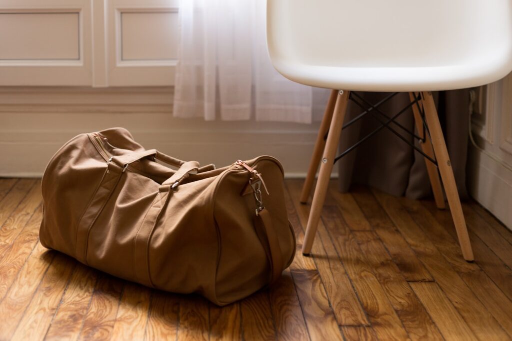 A brown duffel bag rests on the floor beside a chair.