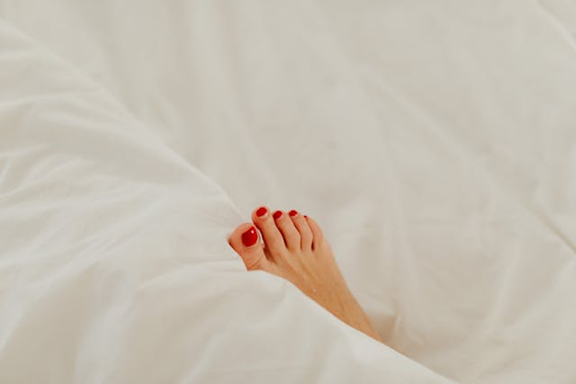 a foot sticking out of the blankets