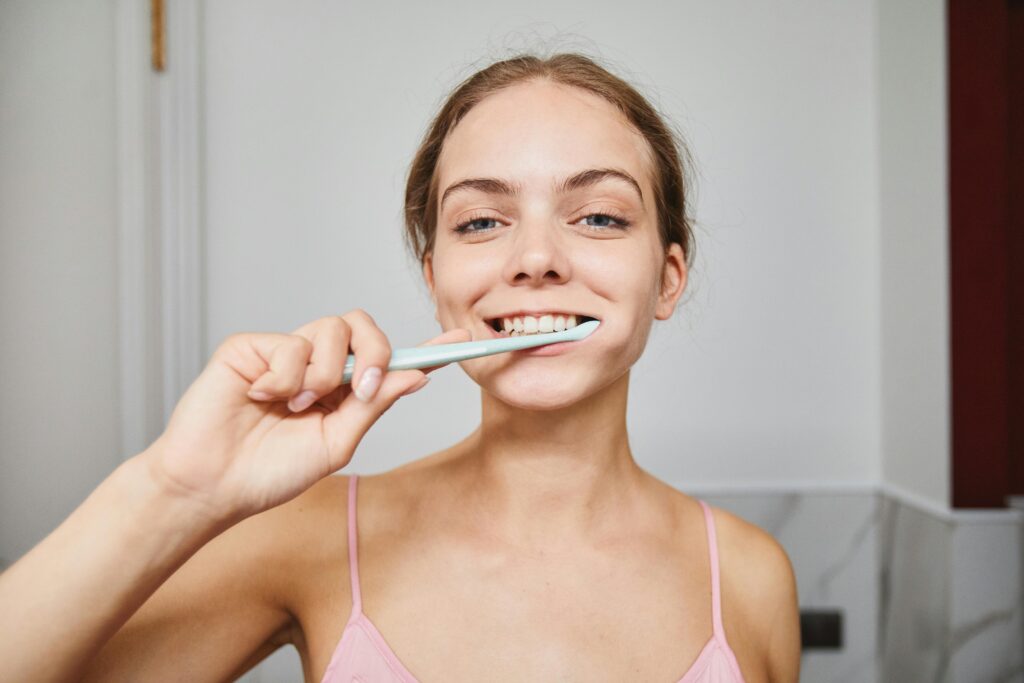 Young woman brushing teeth to maintain oral hygiene.
