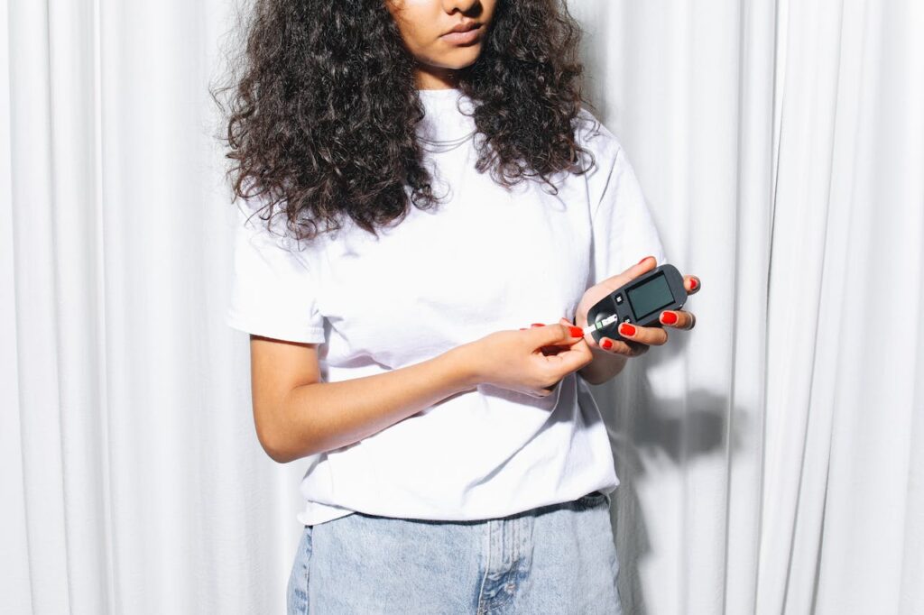 Woman in White Shirt Holding a Glucometer
