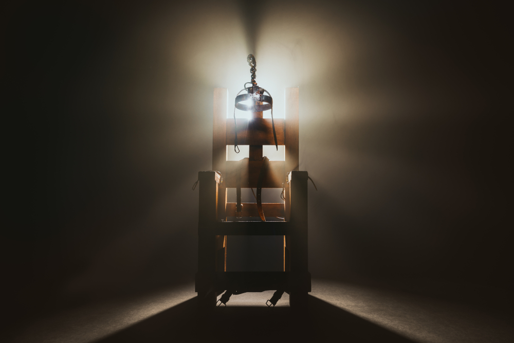 High contrast image of an electric chair scale model on a dark backgorund with smoke