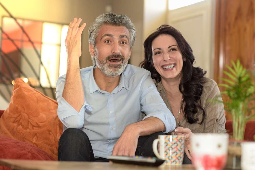 middle-age couple watchs a soccer match on TV