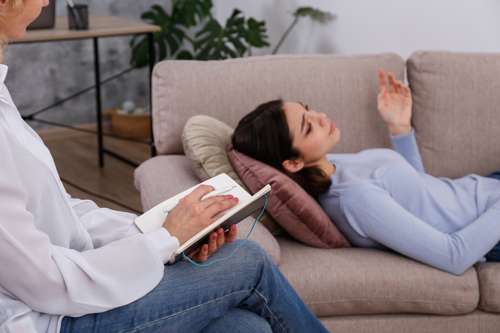 Young woman in distress on a psychological therapy session. A conversation between psychologist and her client in the office. Copy space, background.