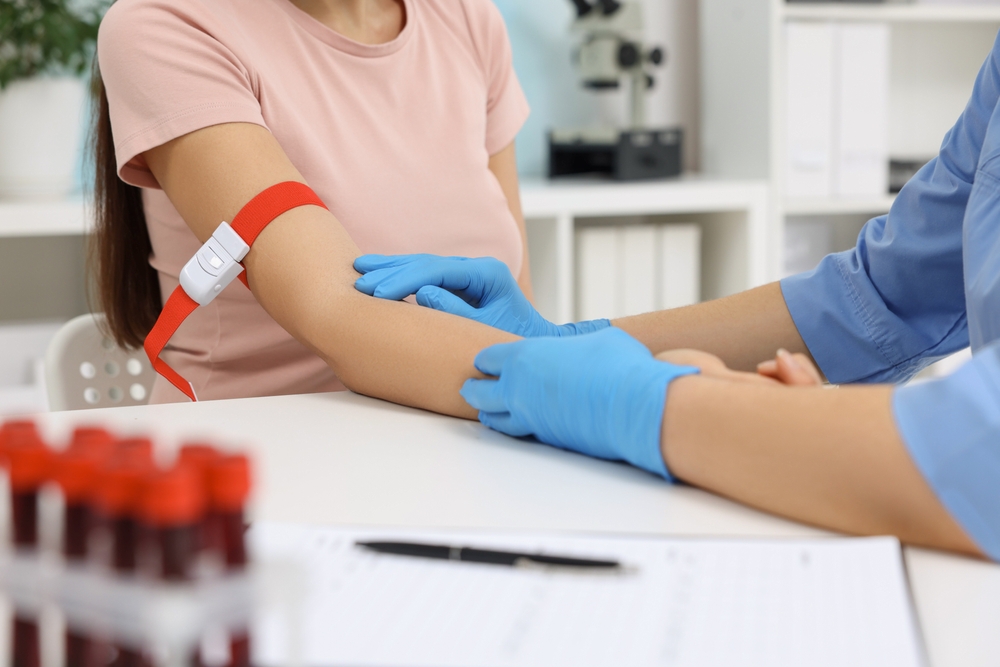 Laboratory testing. Doctor taking blood sample from patient at white table in hospital, closeup