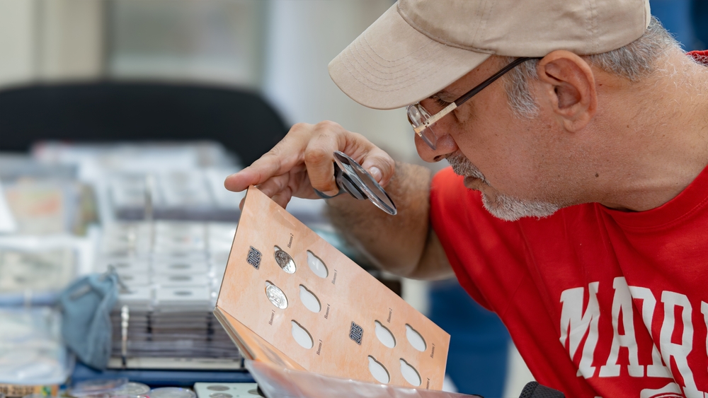 8th Feria de Coleccionismo de Guayaquil. GUAYAQUIL, ECUADOR - AUG 04, 2024 - A coin collector inspects to details of a coin using a magnifying glass A numismatic store showcasing its wares at the fair