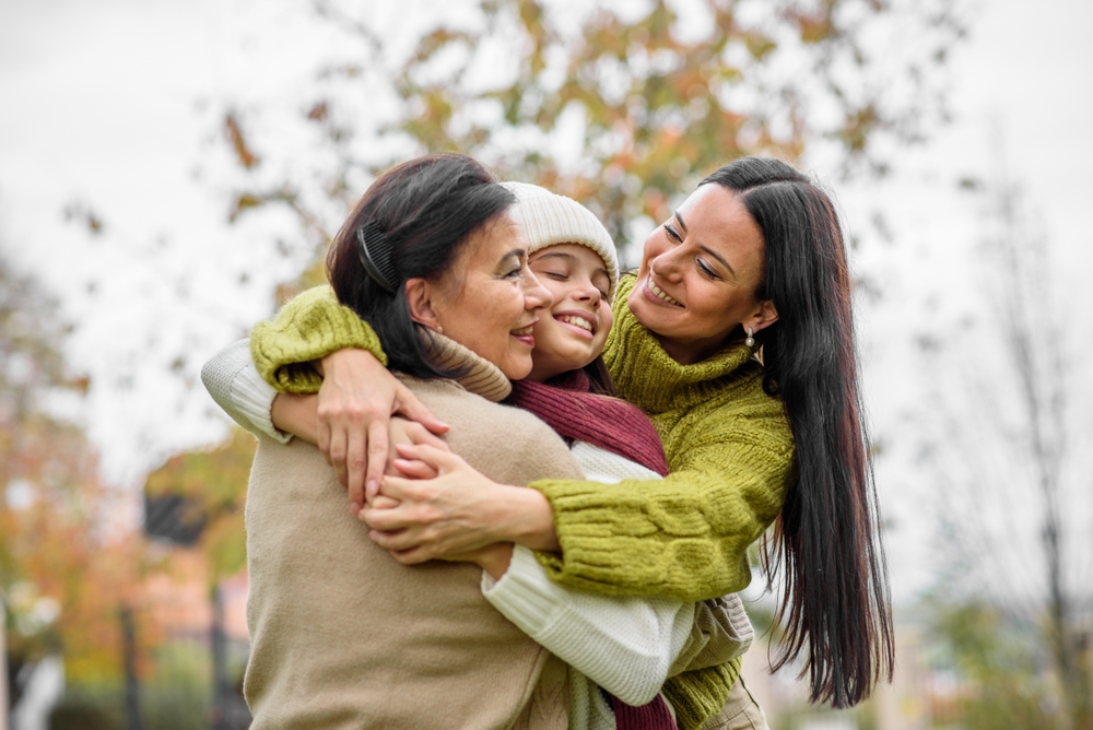 Mature daughter, grandmother and granddaugter hugging. Mother's day and multigenerational family concept.