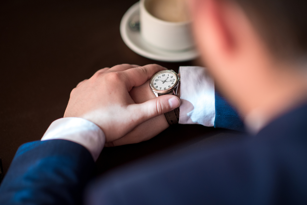 Bearded young successful businessman punctual keeps track of time, a man in a suit waits for the client