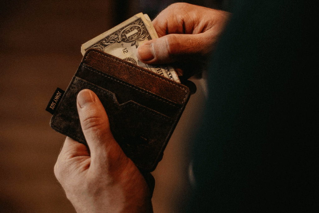 hands opening wallet and taking out a single dollar bill