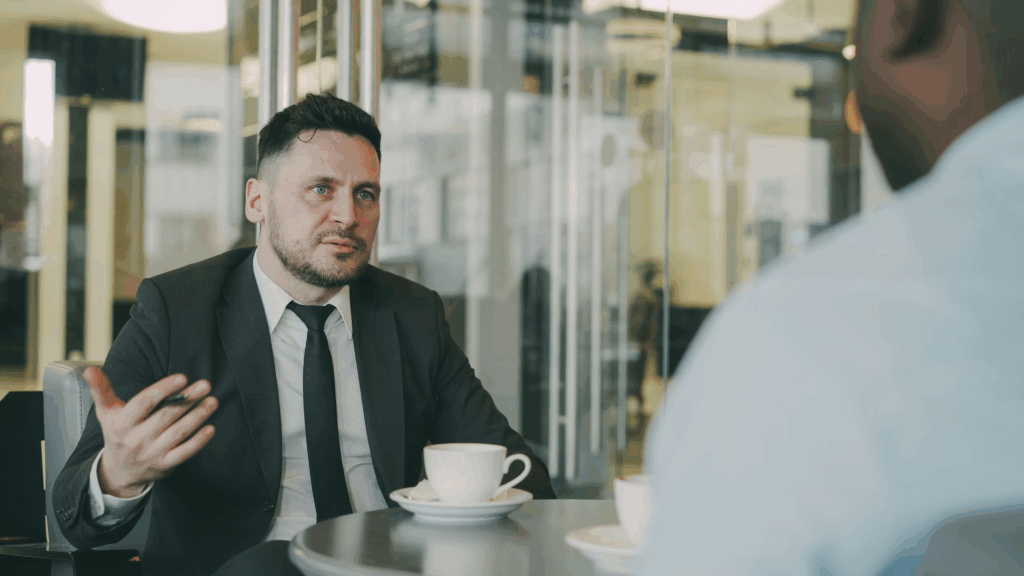 to men at a table with coffee talking