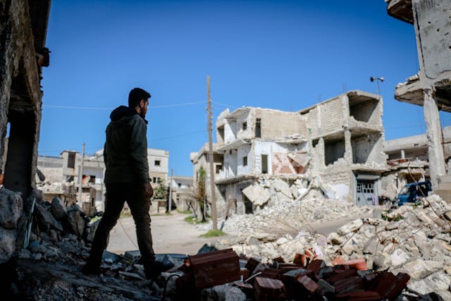 man walks through war-torn city