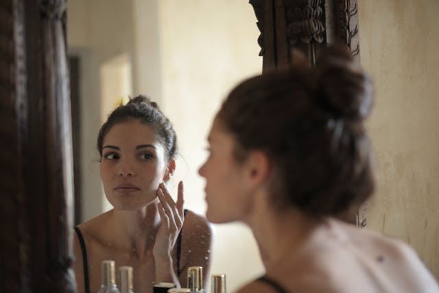 woman looking at her skin in the mirror