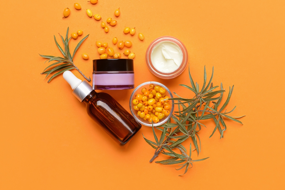 Healthy sea buckthorn cosmetics on color background