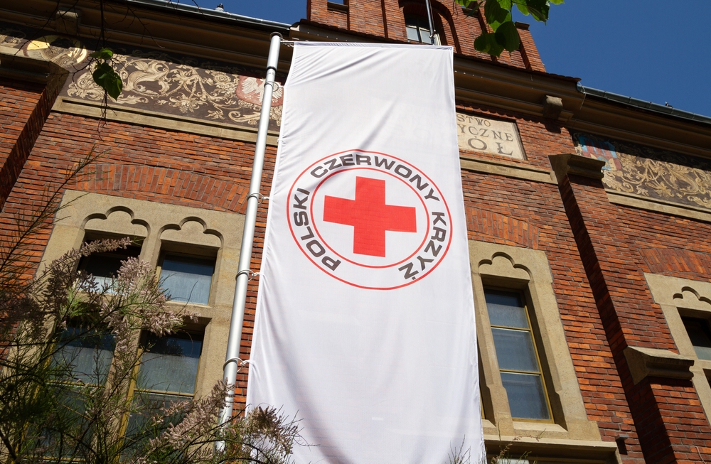 KRAKOW, POLAND - MAY 19, 2022: Polish Red Cross (Polski Czerwony Krzyż, PCK), part of International Red Cross and Red Crescent humanitarian movement. Flag with logo in front of Kraków branch.