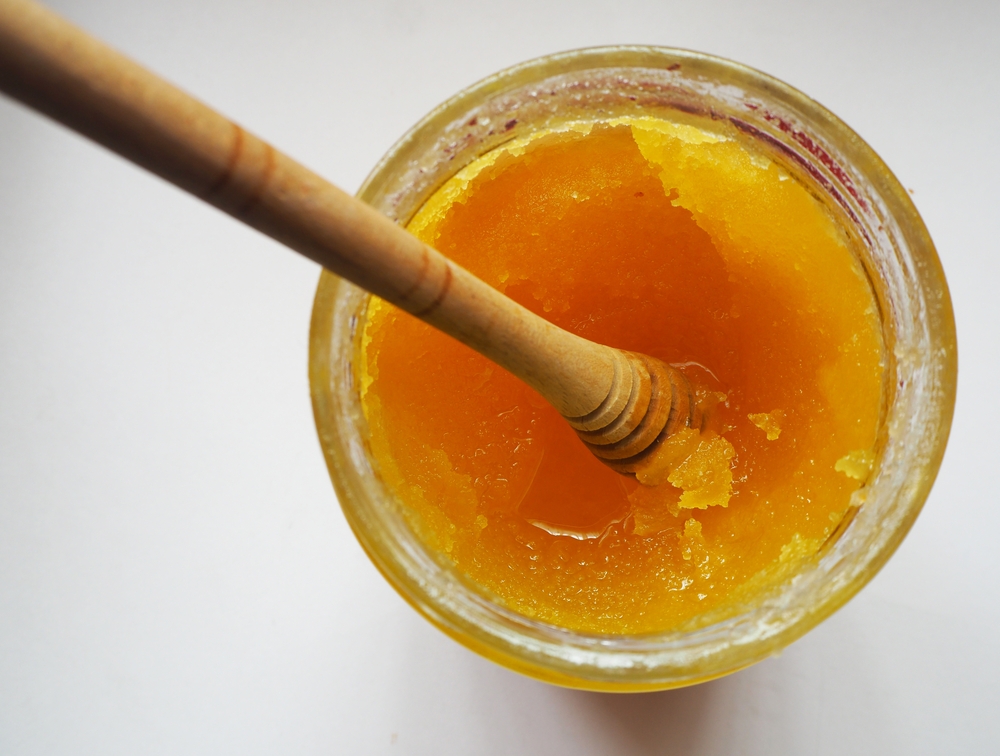 Isolated crystallized honey in a glass jar. Focused on caramelized part.