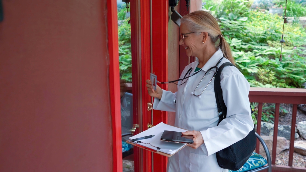Making a rural house call, a mature female doctor or nurse walks to the door, knocks, smiles and shows ID badge.