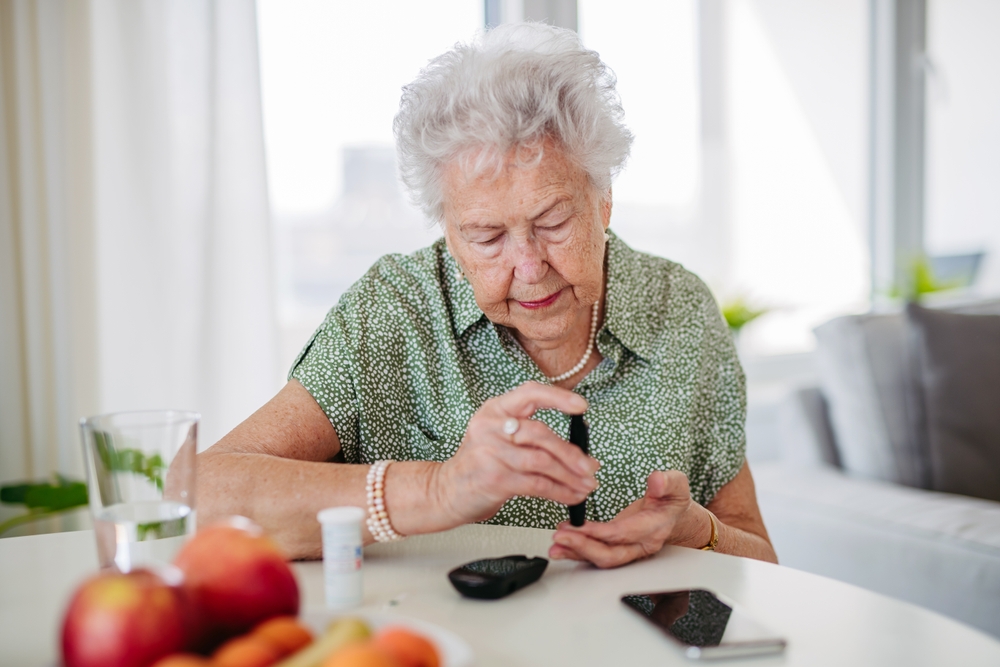 Diabetic senior patient checking her blood sugar level with fingerstick testing glucose meter.