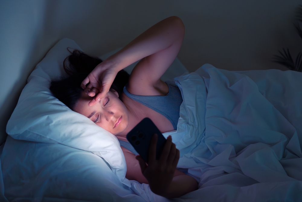 Nocturnal struggles: A woman's battle against insomnia and social media addiction unfolds in the soft glow of her phone