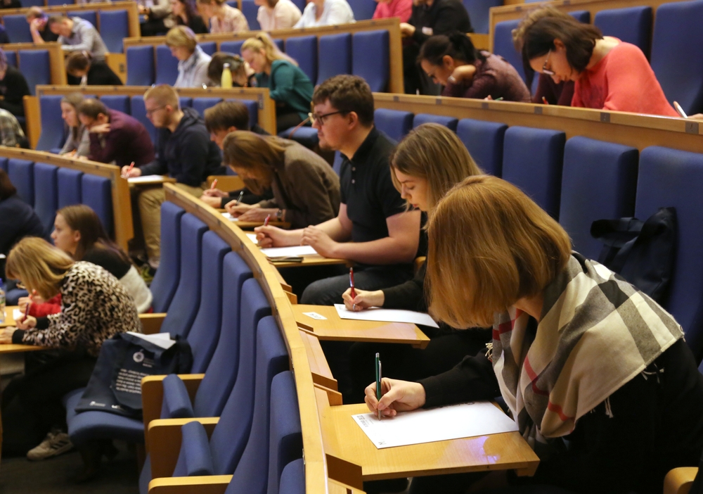 Cracow, Malopolska, Poland - 03.09.2024: Young people writing an exam in a large university auditorium