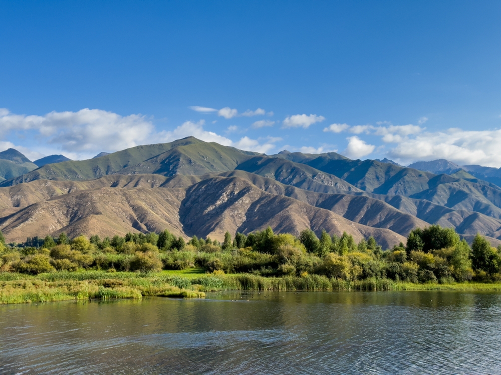 A quiet mountain lake Issyk-Kul, surrounded by green valleys and majestic mountains. The perfect spot for tourism and peaceful relaxation in Kyrgyzstan