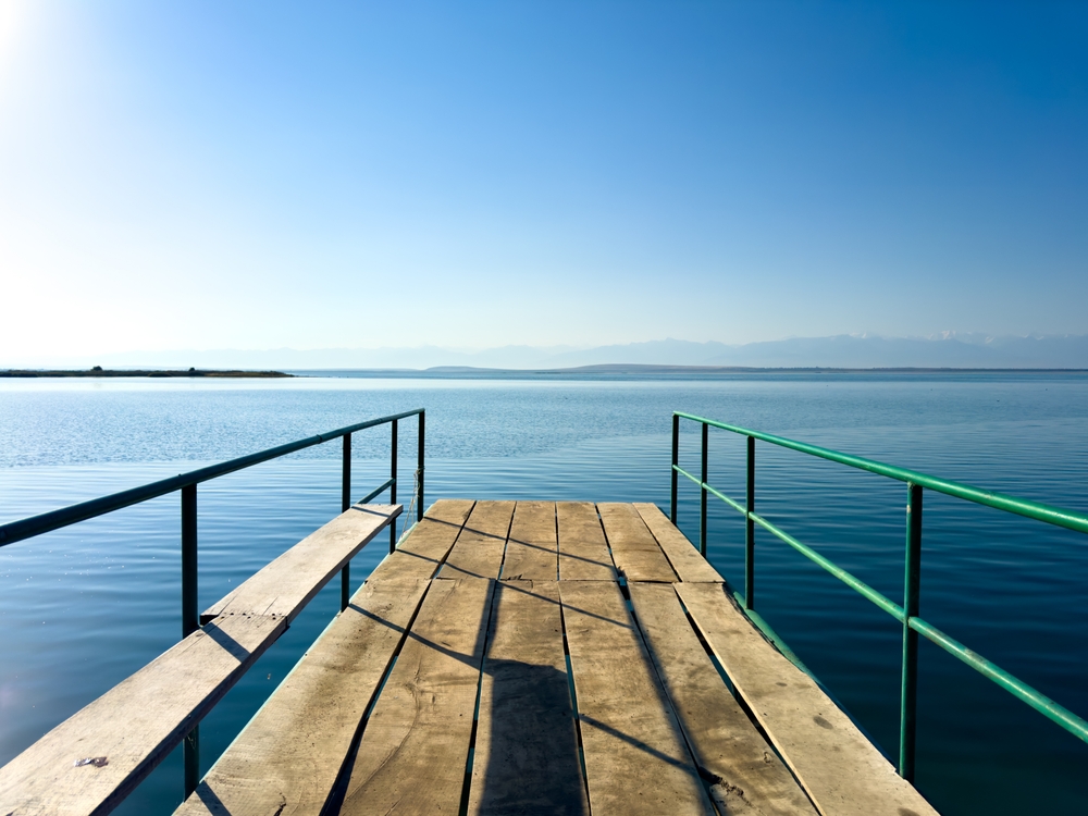 A wooden pier on Issyk-Kul lake with a view of the mountains. A beautiful spot for relaxation and enjoying the natural landscapes of Kyrgyzstan.