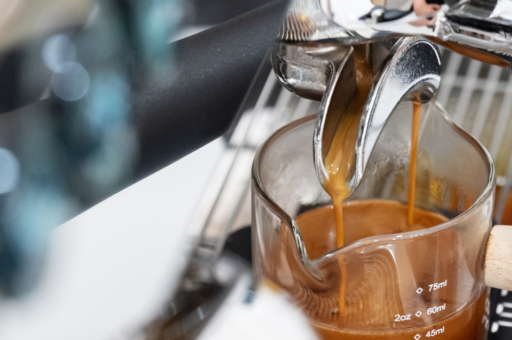 Coffee machine brewing espresso in to glass cup.Barista while preparing and working with coffee machine and making espresso coffee from arabica coffee beans.