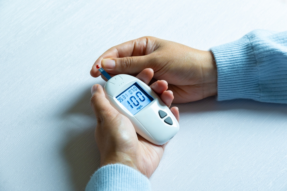 Woman's hands checking diabetes and hyperglycemia with digital blood sugar meter. Healthcare and medical concept