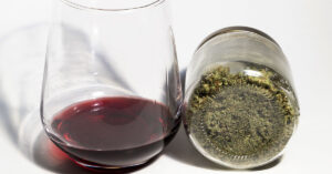 Psychiatrist Weighs In: Alcohol vs. Cannabis Risks After New Side Effect Emerges Glass of wine and a jar containing cannabis on its side